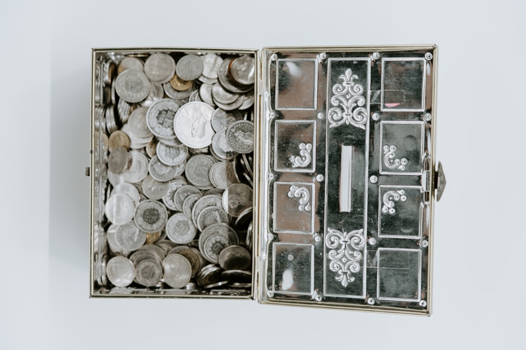 Miniature model of a modern house sits atop a growing stack of coins against a clean, bright background, symbolizing incre...