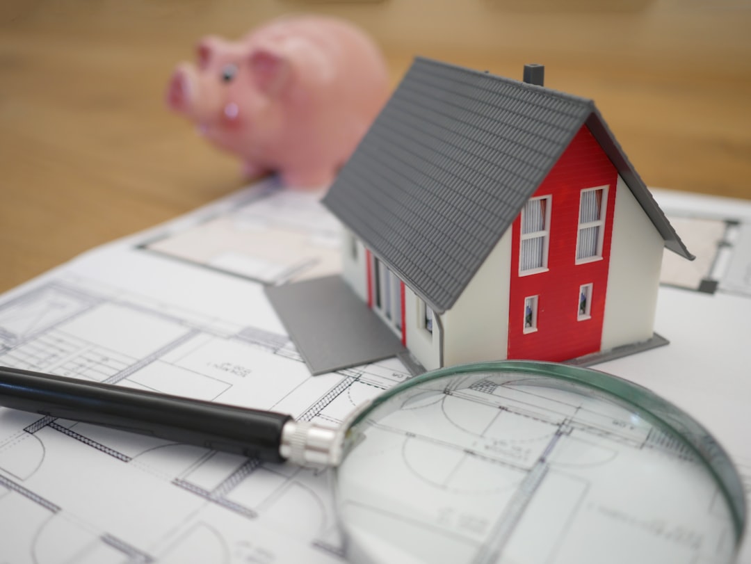 Small white model of a house sits next to a piggy bank on a clean, bright surface, symbolizing saving money on real estate.