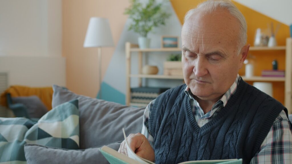 Serious couple sits at their kitchen table with a laptop and documents, looking concerned as they review the high costs as...