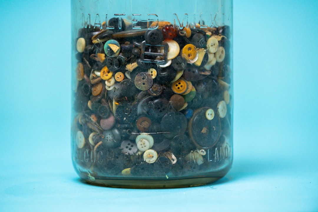 A close-up shot of a glass jar being filled with coins, with a house key inside, symbolizing saving money for a down payment.