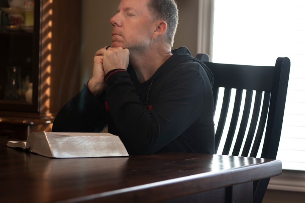 Homeowner sits at their kitchen table looking overwhelmed by a pile of documents and a laptop, representing the stress of ...