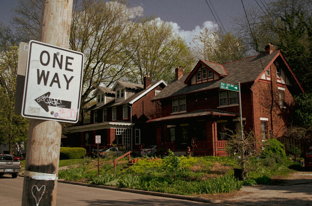 A professional 'Sold' sign standing in the green front yard of a lovely suburban house, indicating a successful home sale.