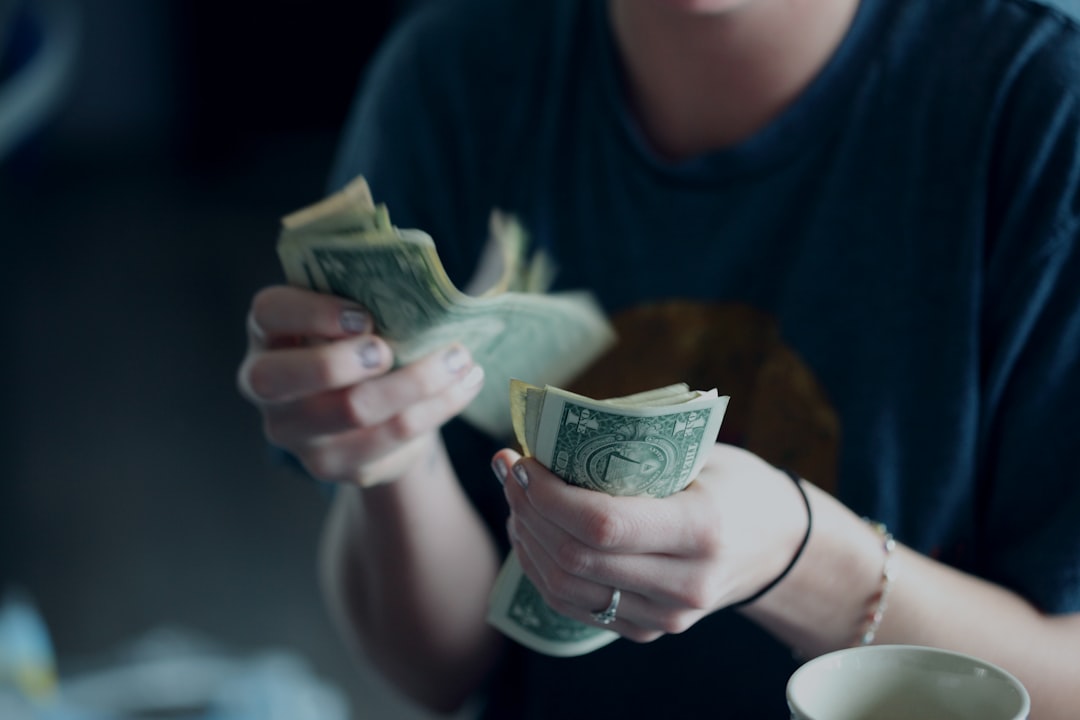 A close-up, brightly lit shot of a person's hands holding a set of house keys and a stack of cash, symbolizing the take-home pay from a home sale.