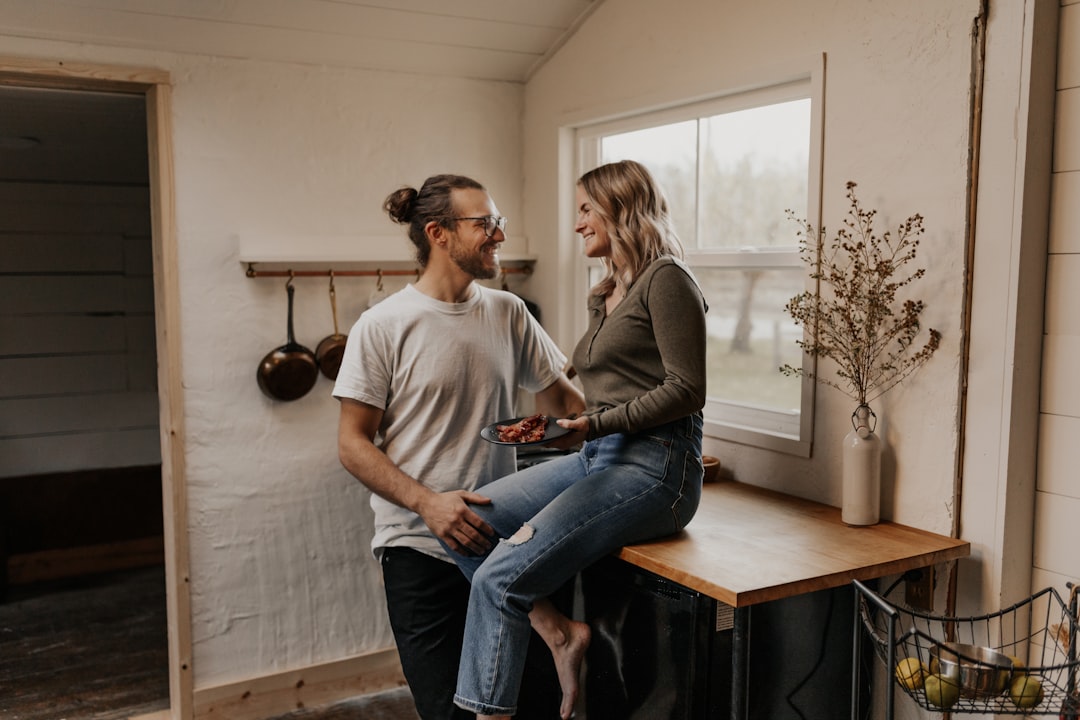 A smiling couple holds up the keys to their new, modern house, representing the successful outcome of upgrading their home through smart savings.