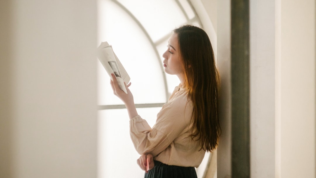 Woman sits at a bright, clean table, thoughtfully looking over financial documents with a calculator, representing the pro...