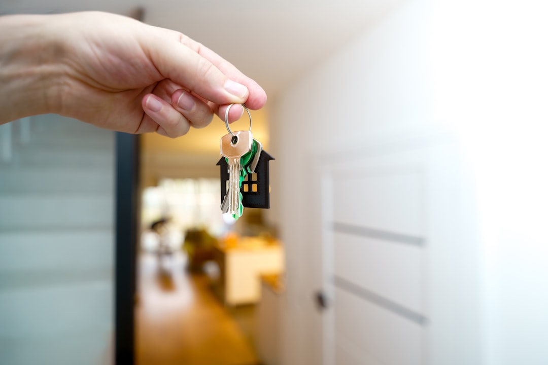 A minimalist photo of a set of house keys resting next to a clean, white piggy bank, symbolizing the financial savings from a 1% real estate commission.