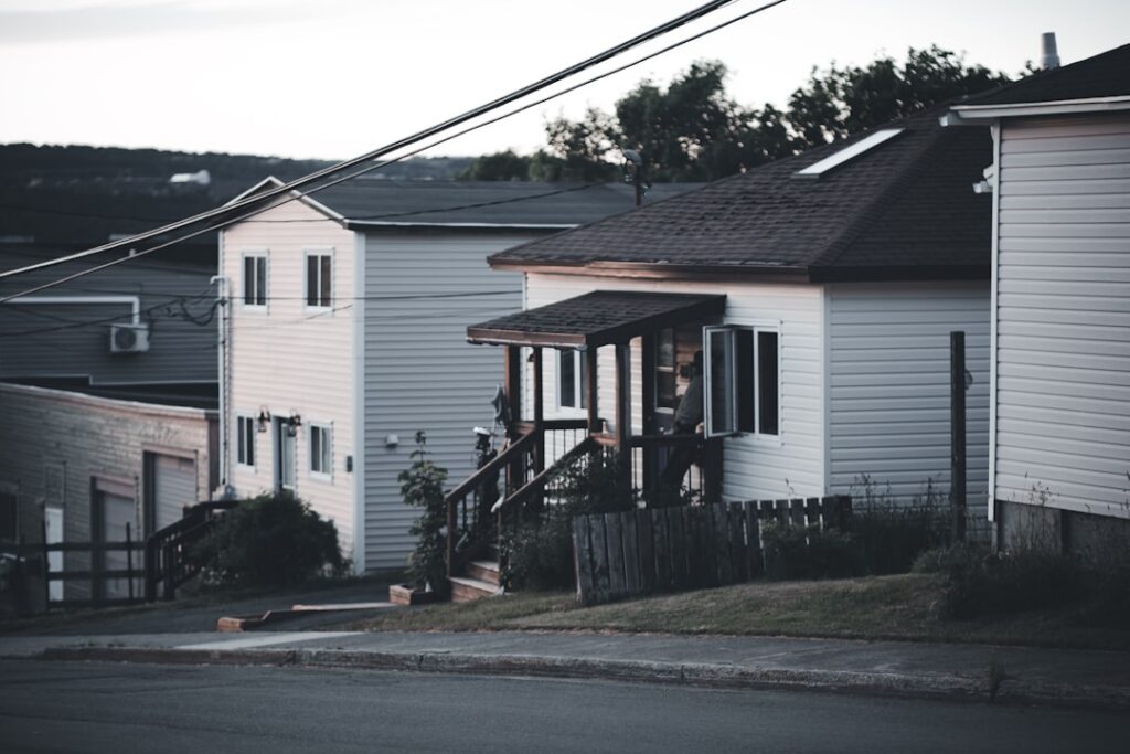 Person stands thoughtfully considering two different modern homes, symbolizing the important choice between real estate se...