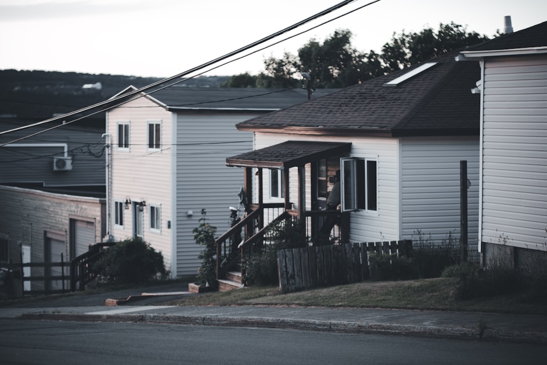 Person stands thoughtfully considering two different modern homes, symbolizing the important choice between real estate se...