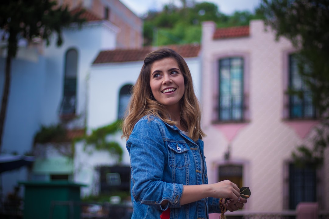 A smiling homeowner proudly holding up the keys in front of their modern house, illustrating the satisfaction of saving money on commission fees.