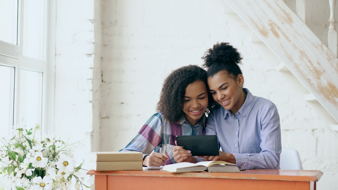 A smiling couple at their dining table with a laptop and coffee, collaboratively planning their financial future by reinvesting savings from their home sale.