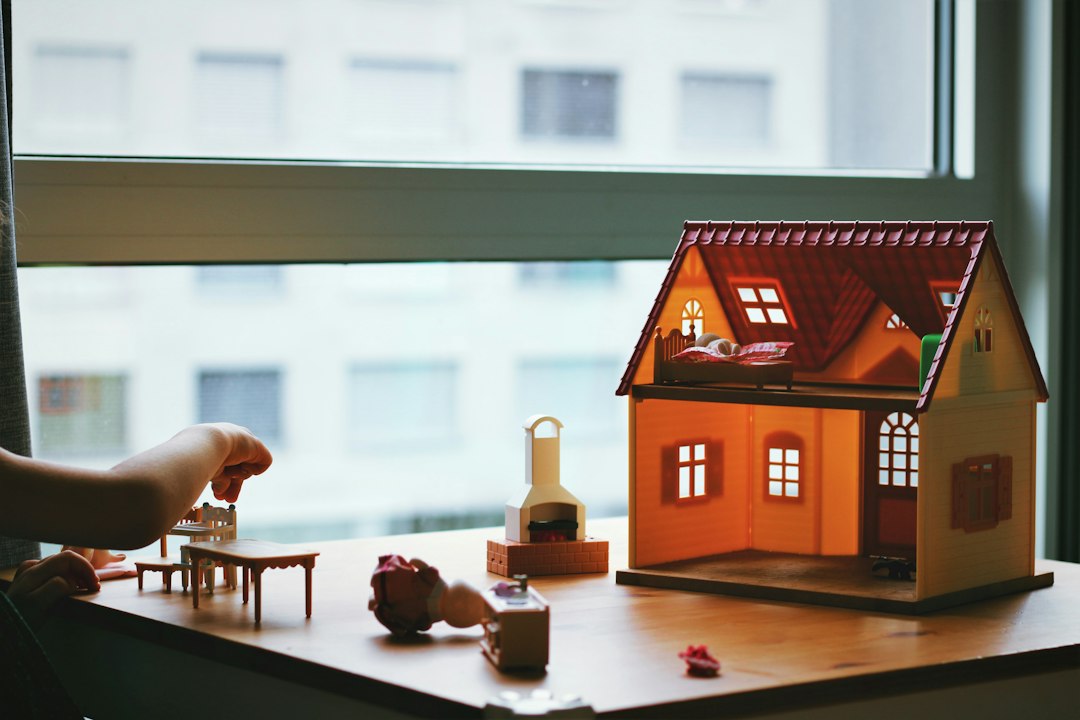 A pair of hands gently holding a small, modern model of a house, representing the protection of home equity and real estate investment.