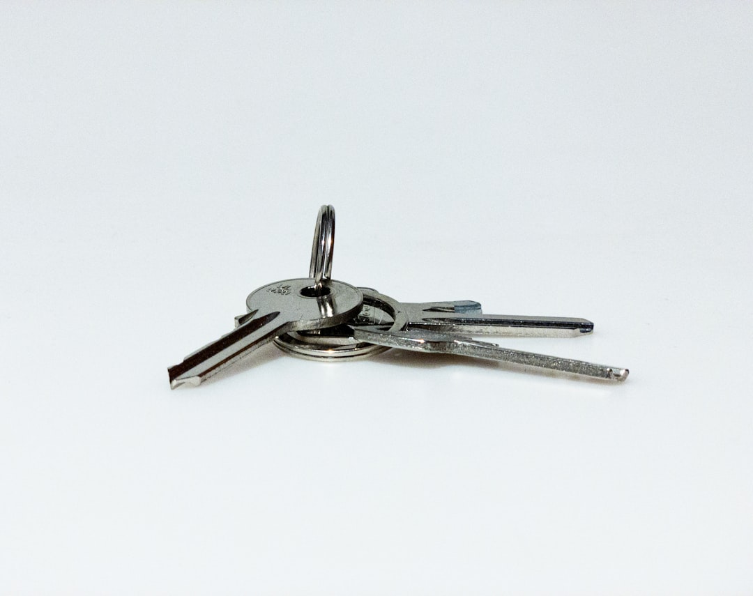 A set of house keys resting on a clean wooden table with a bright, beautiful home interior softly blurred in the background, signifying a successful home sale.