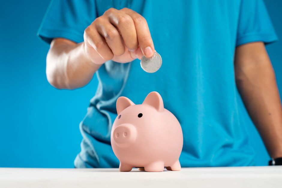 A ceramic piggy bank sitting on a set of rolled architectural blueprints, symbolizing saving money and increasing net profit from a home sale.