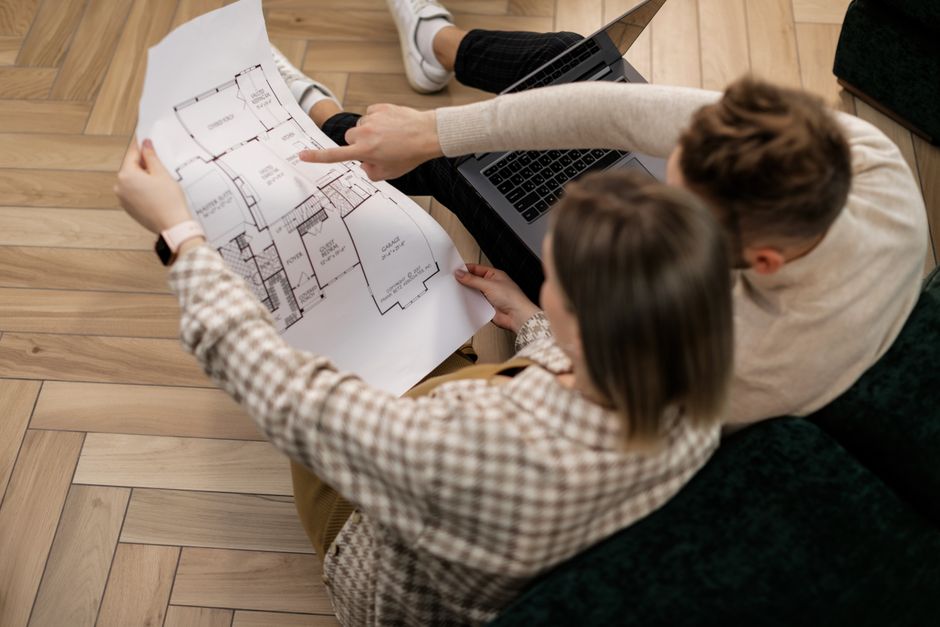A couple sits together in their modern living room, thoughtfully reviewing documents, representing the important decisions involved in a home sale.