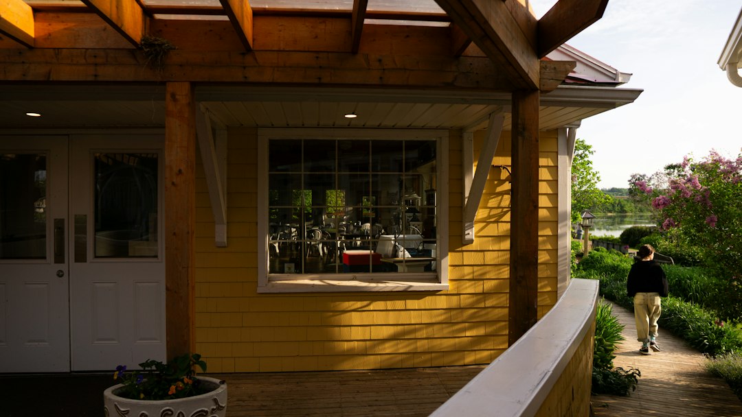 A person's hand holding house keys, with a beautiful modern suburban home blurred in the background on a sunny day, representing a successful home sale.